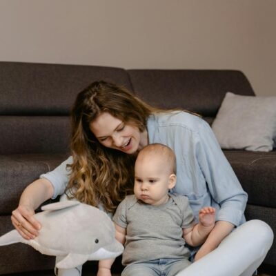 A Woman Sitting on the Floor while Playing with Her Baby