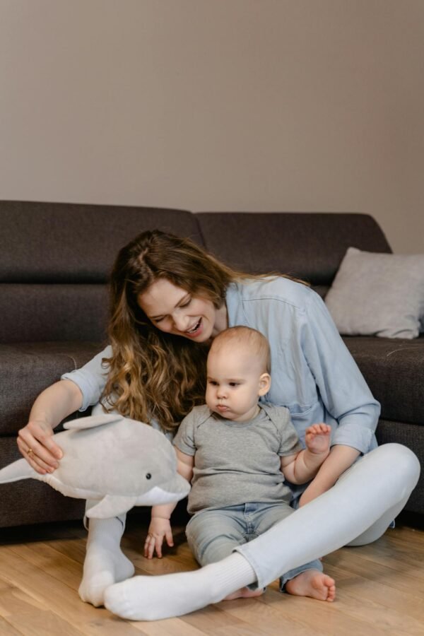 A Woman Sitting on the Floor while Playing with Her Baby