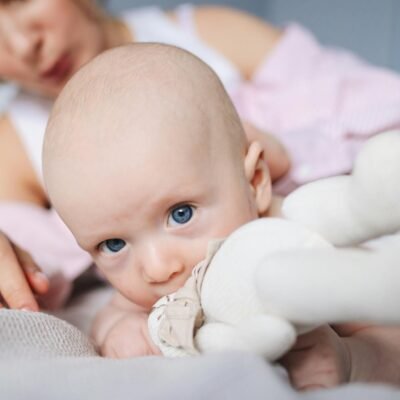 Cheerful baby with mother on bed