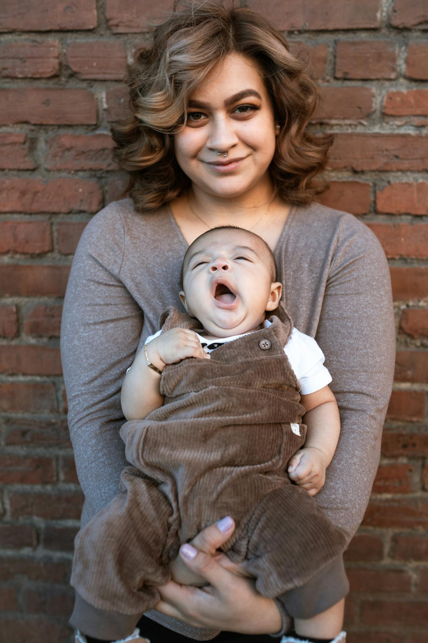 Woman in Gray Long Sleeve Shirt Carrying Baby in White Shirt